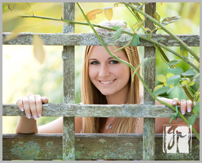beautiful senior girl looking through a fence